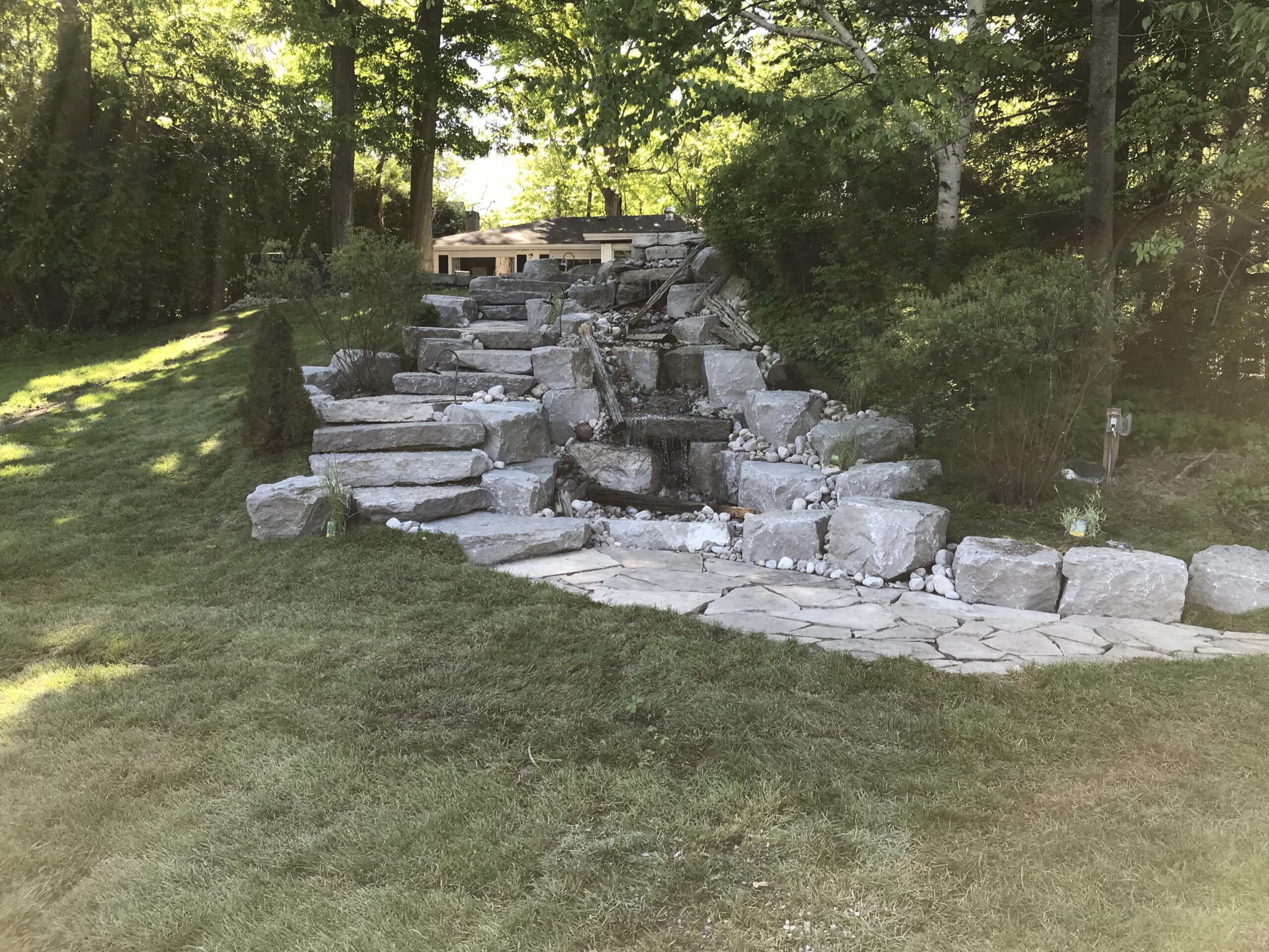 Natural stone waterfall installation in a landscaped garden